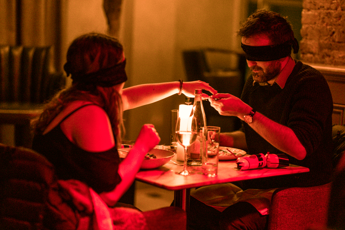 A couple holding hands at the Dining in the Dark experience.