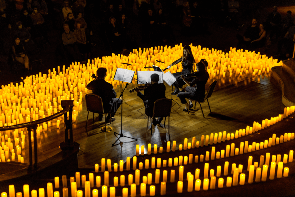 String quartet performing surrounded by candles