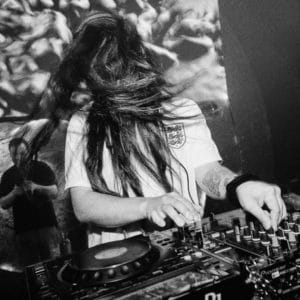 Black and white photo of DJ behind decks dancing