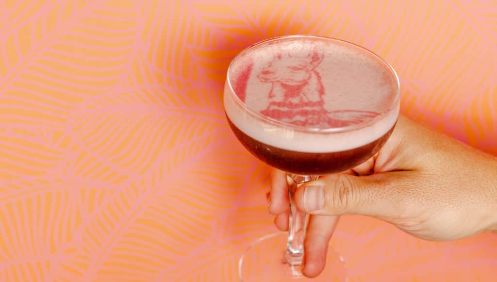 Pink cocktail with llama stencil on top