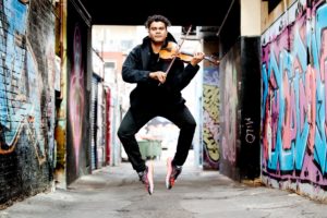 Eric Avery playing violin in a graffitied laneway