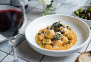 Bowl of pumpkin and sage gnocchi with glass of red wine