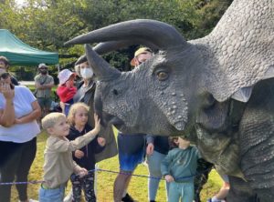 Children up close to a life-sized dinosaur replica in parklands