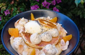 Bowl of carefully curated pancaes with oranges and clouds of cream