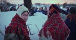 Still from the movie Let The River Flow, two girls in traditional clothing in a winterscape