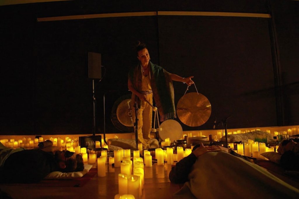 A woman performing a candlelit sound bath.