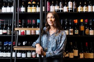 Emma Farrelly stands in front of a wall of wine