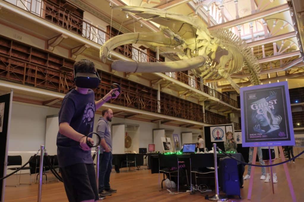 Person wearing VR goggles standing in front of a huge whale skeleton hovering mid-air